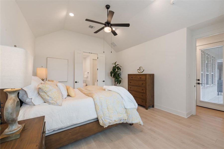 Relax in this well-lit bedroom featuring high vaulted ceilings and light wood flooring. Relax in this well-lit bedroom featuring high vaulted ceilings and light wood flooring.