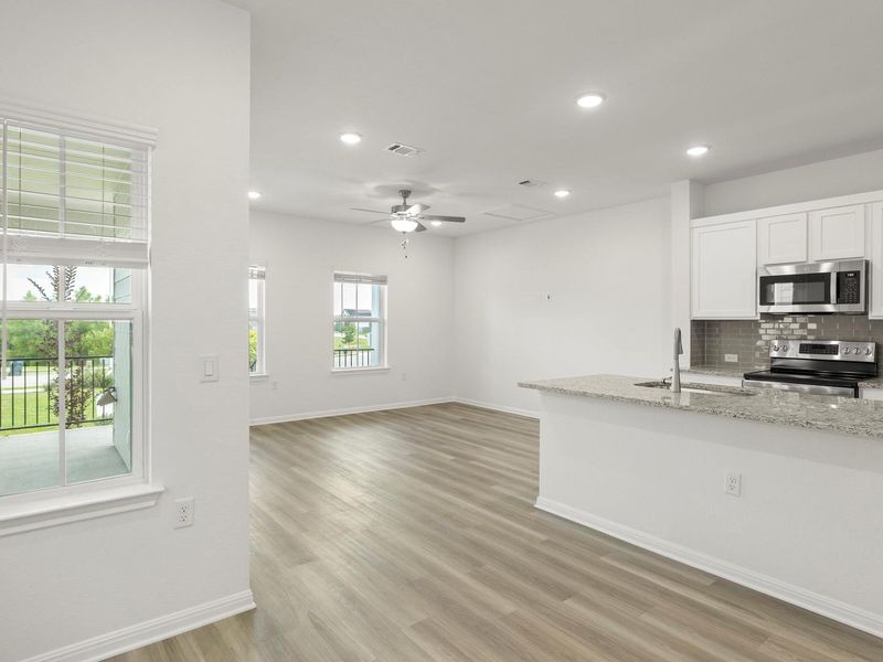 Natural light floods this modern living space with an open-concept kitchen and wood flooring.