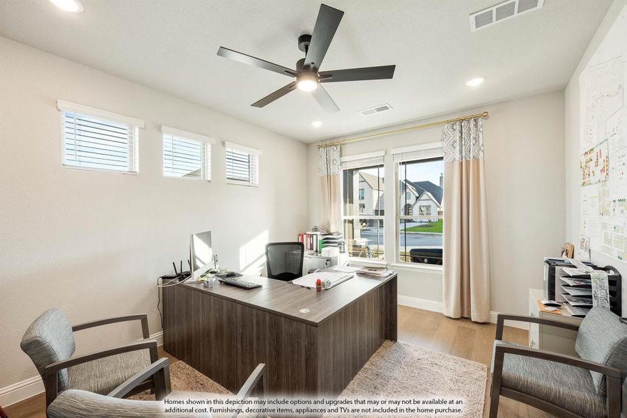 Home office with L-shaped wood desk, ceiling fan, hardwood floors, and large window with curtains