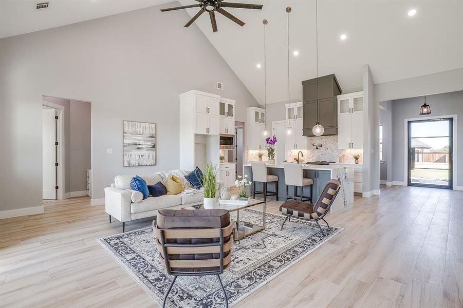 Living room with high vaulted ceiling, ceiling fan, recessed lighting, and light wood finished floors