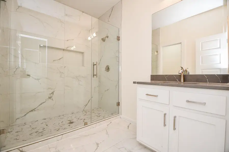 Secondary full bathroom with walk-in shower surrounded by polished porcelain tile walls, single vanity with quartz countertop. Secondary full bathroom with walk-in shower surrounded by polished porcelain tile walls, single vanity with quartz countertop.