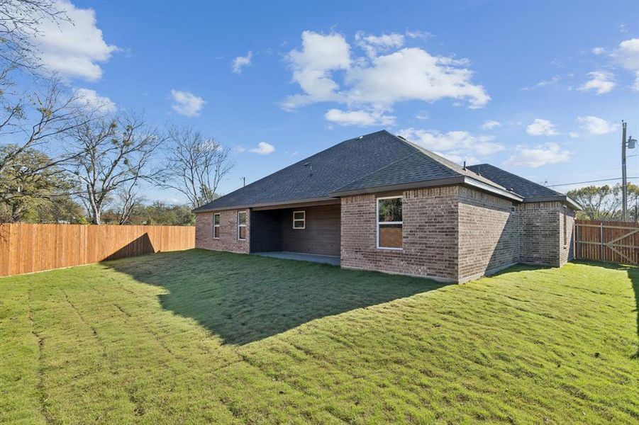 Back of property with a fenced backyard, a patio area, brick siding, and a shingled roof