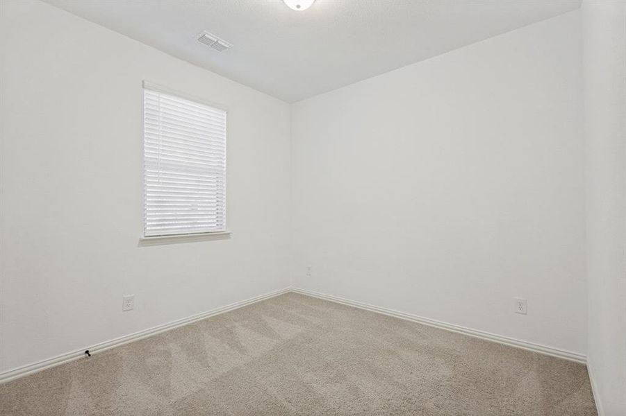 Neutral-toned room featuring a single window with blinds, light beige carpet, white baseboards, and a ceiling-mounted light fixture