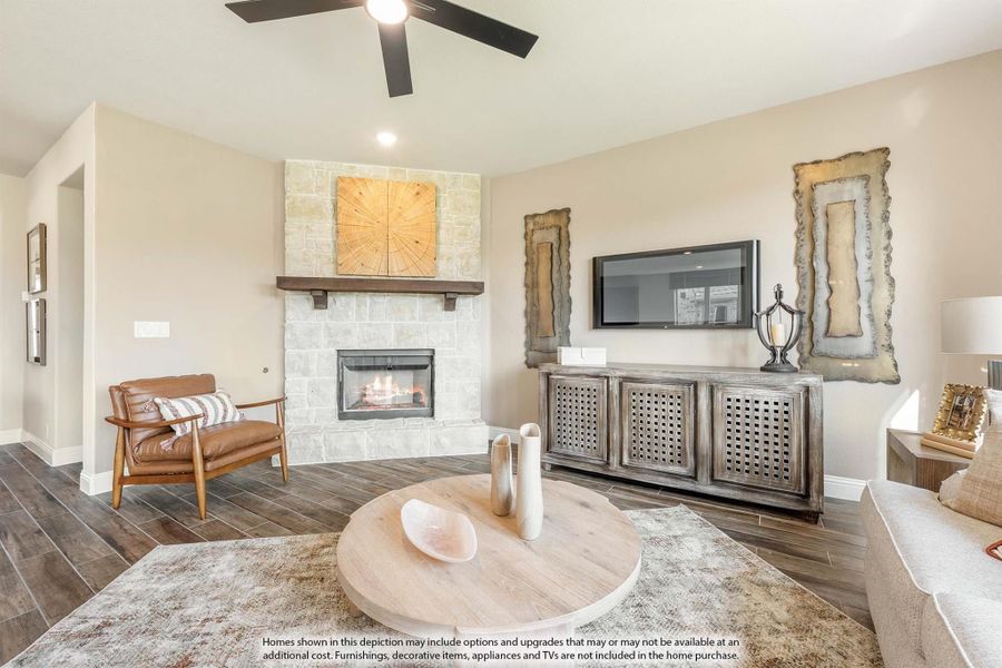Living room with stone fireplace, ceiling fan, hardwood floors, and rustic wood media console Living room with stone fireplace, ceiling fan, hardwood floors, and rustic wood media console