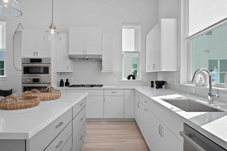 Kitchen with plenty of natural light, white cabinets, pendant lighting, and light wood-type flooring