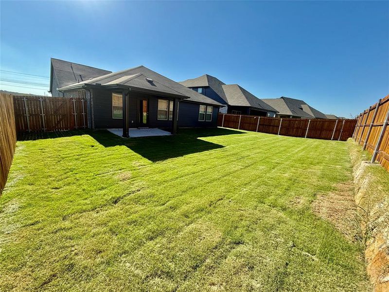 Expansive backyard featuring a covered patio with concrete flooring, wood privacy fencing, and a large grassy area Expansive backyard featuring a covered patio with concrete flooring, wood privacy fencing, and a large grassy area