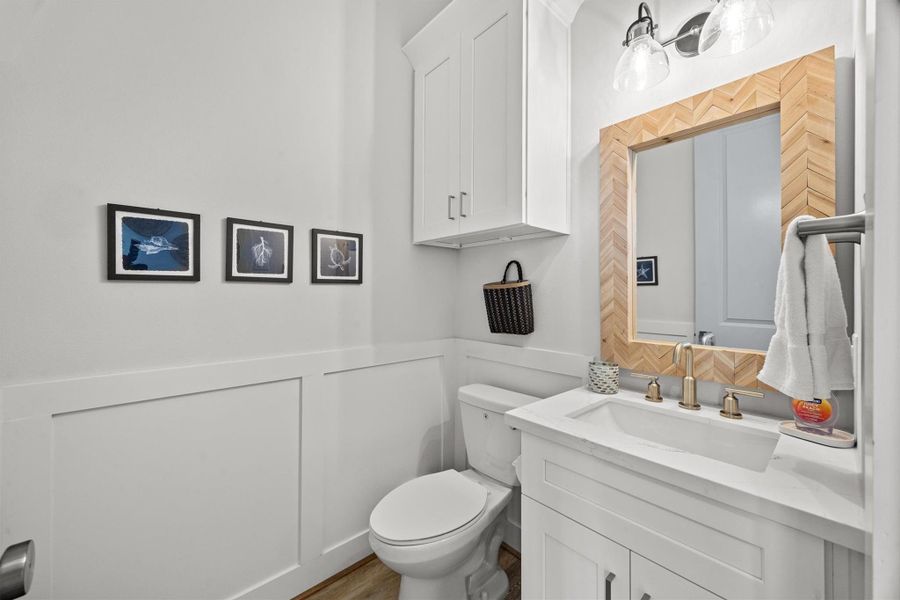 The half bath, located on the first floor, features detailed millwork that adds a coastal, playful touch to the space.