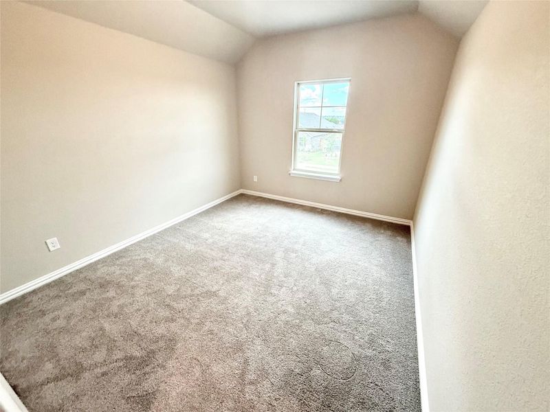 Carpeted empty room featuring vaulted ceiling and baseboards Carpeted empty room featuring vaulted ceiling and baseboards