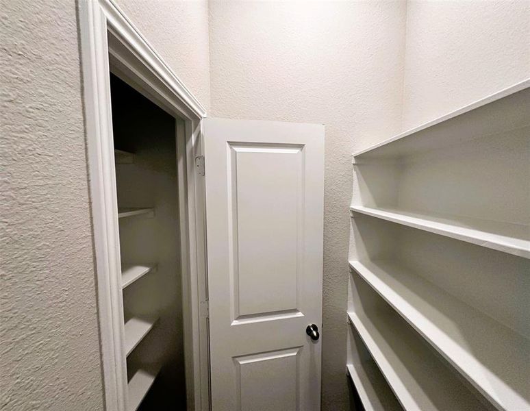 Another view of the laundry room featuring storage shelves & a storage closet.