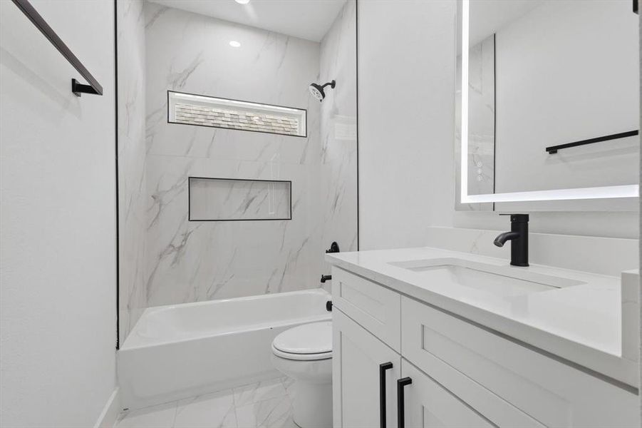 Bathroom featuring shower / tub combination, vanity, and light marble finish floors Bathroom featuring shower / tub combination, vanity, and light marble finish floors
