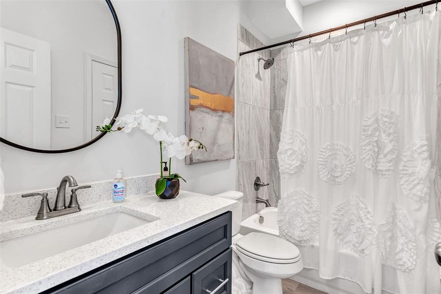 Full bathroom featuring vanity, shower / bathtub combination with curtain, and toilet