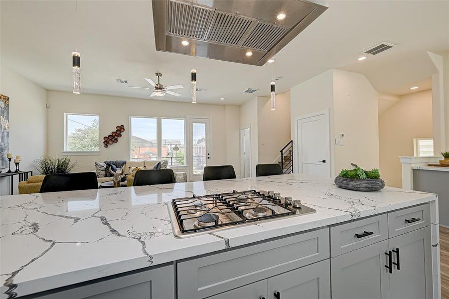 Check out the elegant pendant lighting and the vent overhead the cooktop.