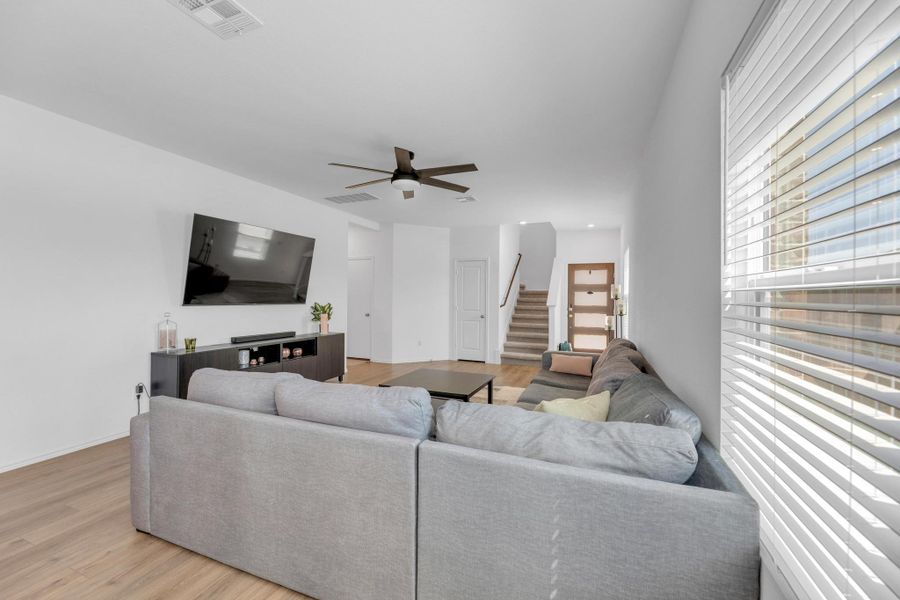 Living area featuring stairs, light wood-style floors, visible vents, and a ceiling fan