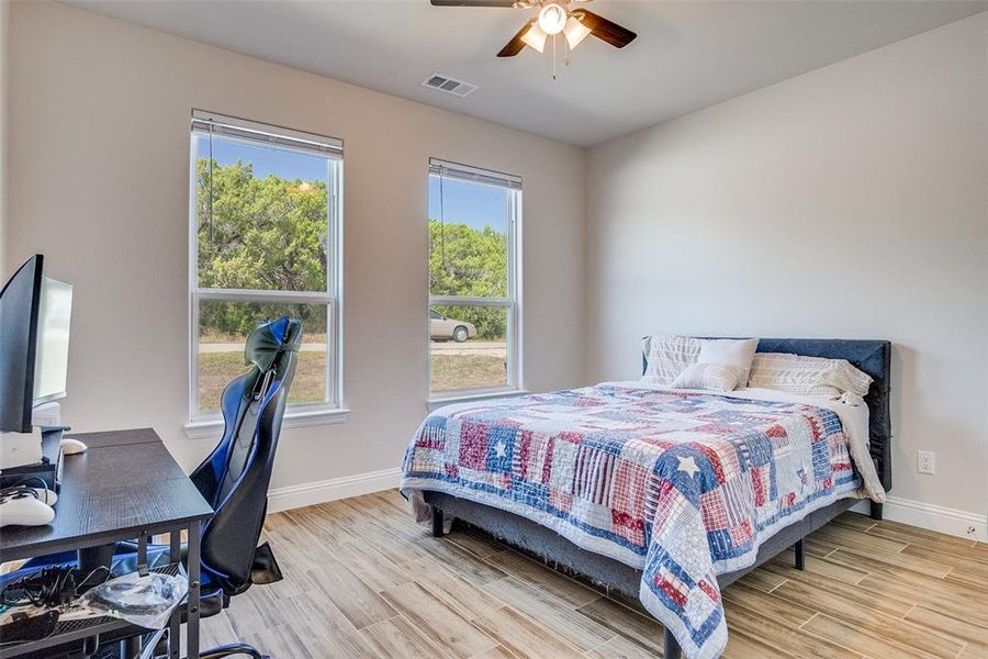 Bedroom with wood tiled floors, an office area, and a ceiling fan