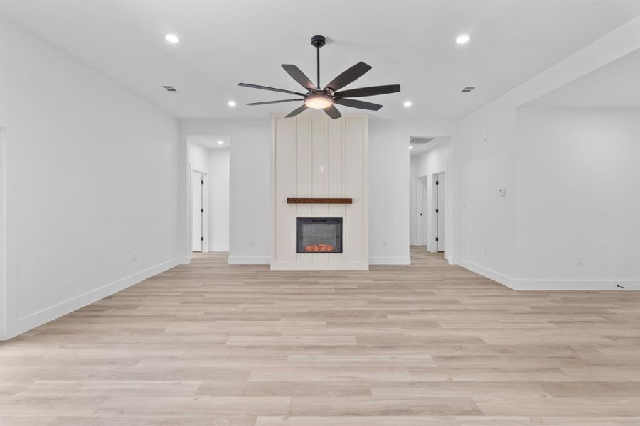 Unfurnished living room featuring light wood-style floors, a large fireplace, recessed lighting, and ceiling fan