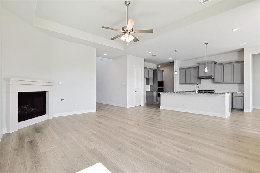 Unfurnished living room with sink, light hardwood / wood-style flooring, and ceiling fan