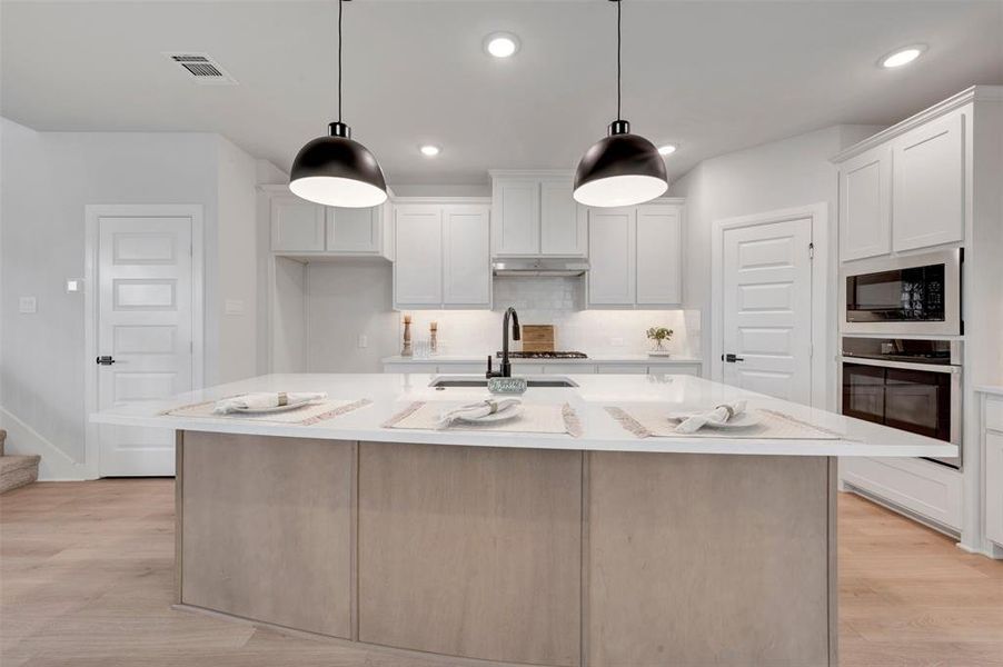 Kitchen featuring a spacious island with a light wood-finish base and light-toned countertop