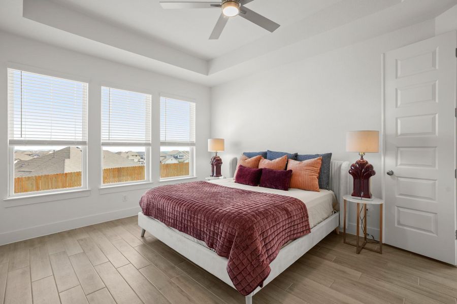 A well-lit bedroom features durable plank flooring and a sleek ceiling fan.