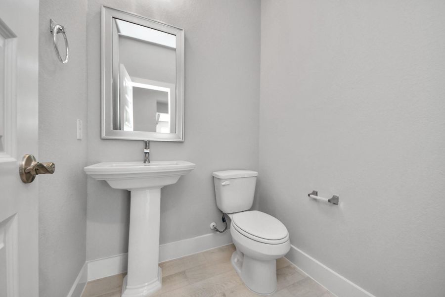 This half bathroom features a stylish pedestal sink, modern hardware, and bright recessed lighting, creating a sleek and inviting space.