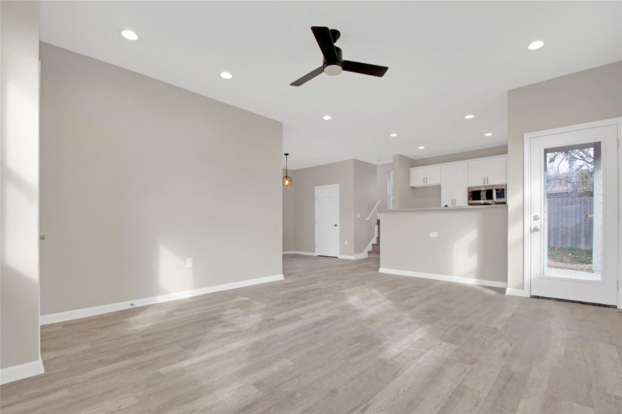 Unfurnished living room with a ceiling fan, recessed lighting, and light wood-style flooring