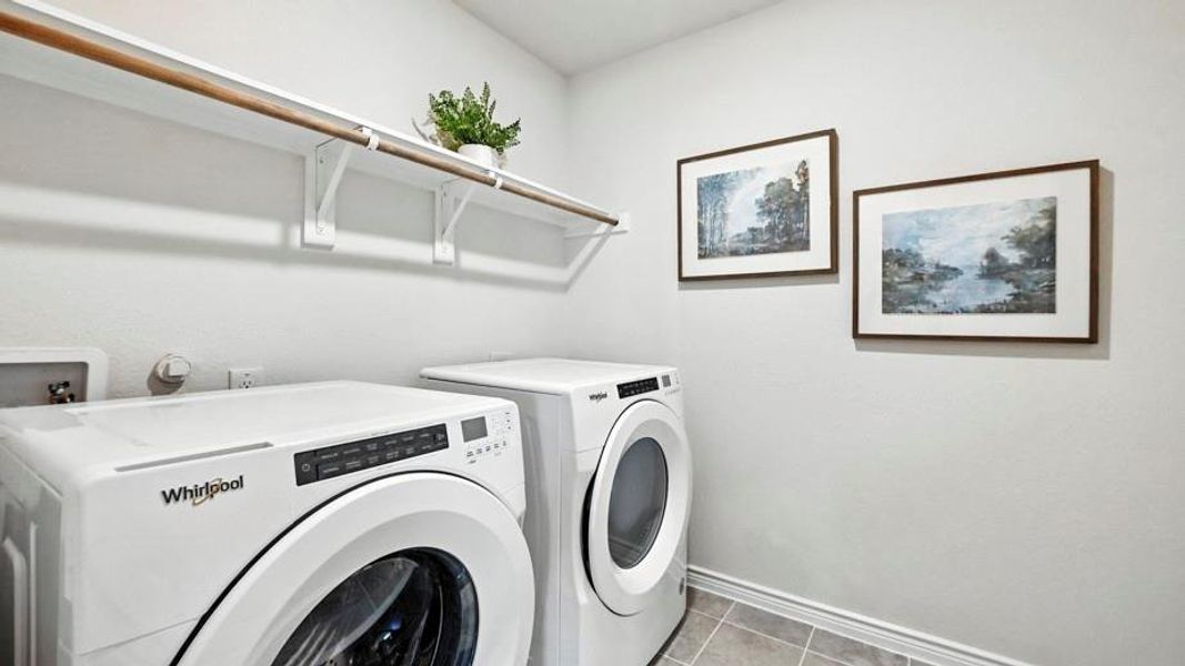 Laundry room featuring white front-loading appliances, a built-in shelf with a wooden rod, and tiled flooring