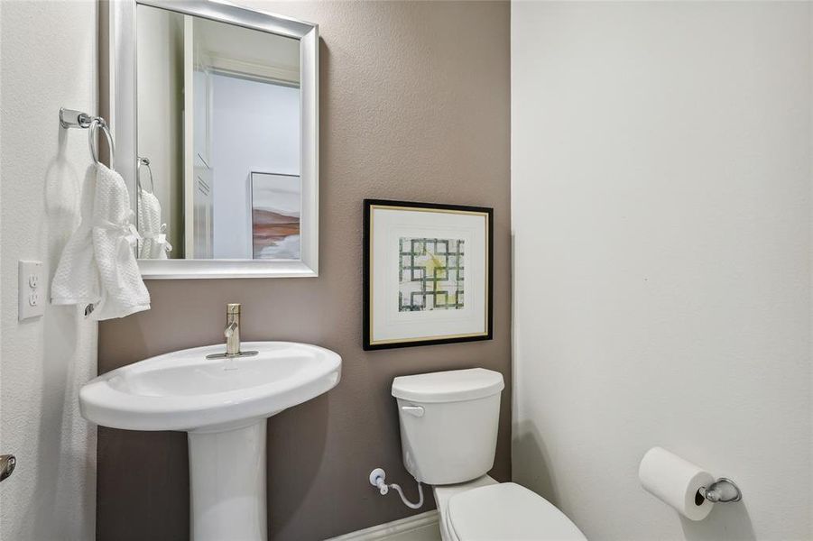 Pedestal sink with polished chrome faucet, framed mirror, and two-tone wall finishes