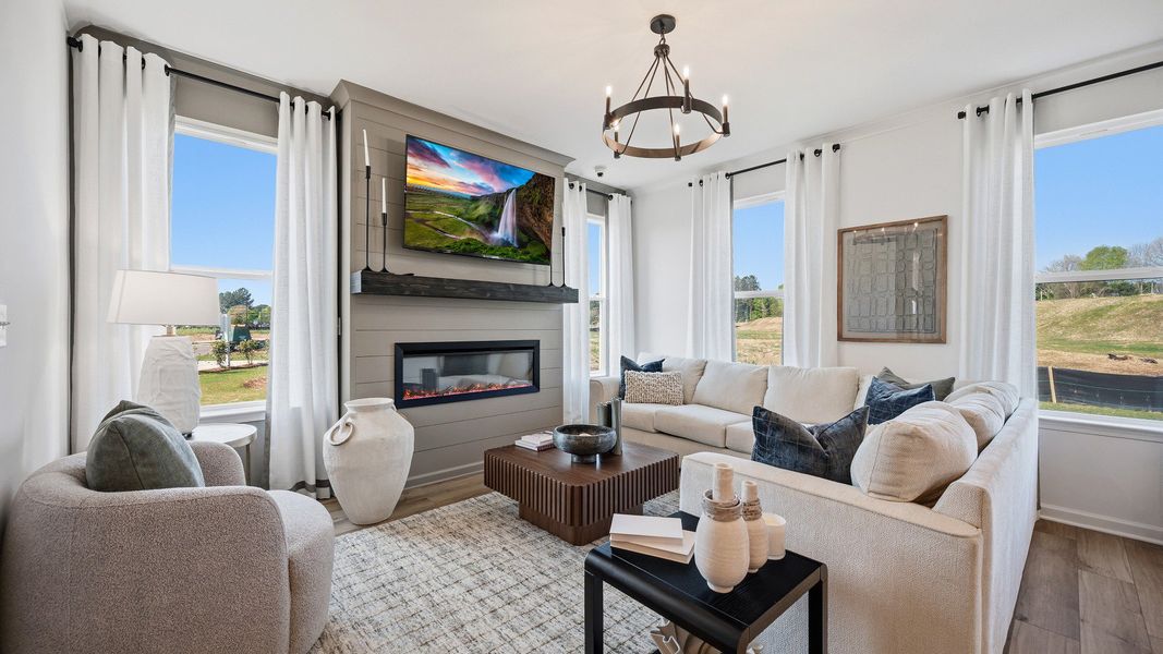 Spacious family room with electric fireplace, large windows, and open layout in Langley Overlook townhome in Loganville, GA.
