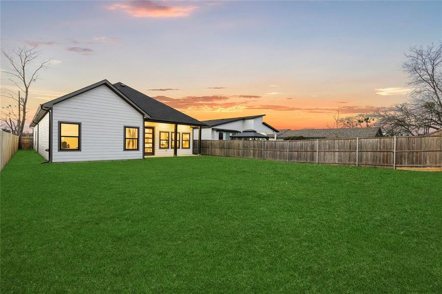 Back house at dusk with a yard