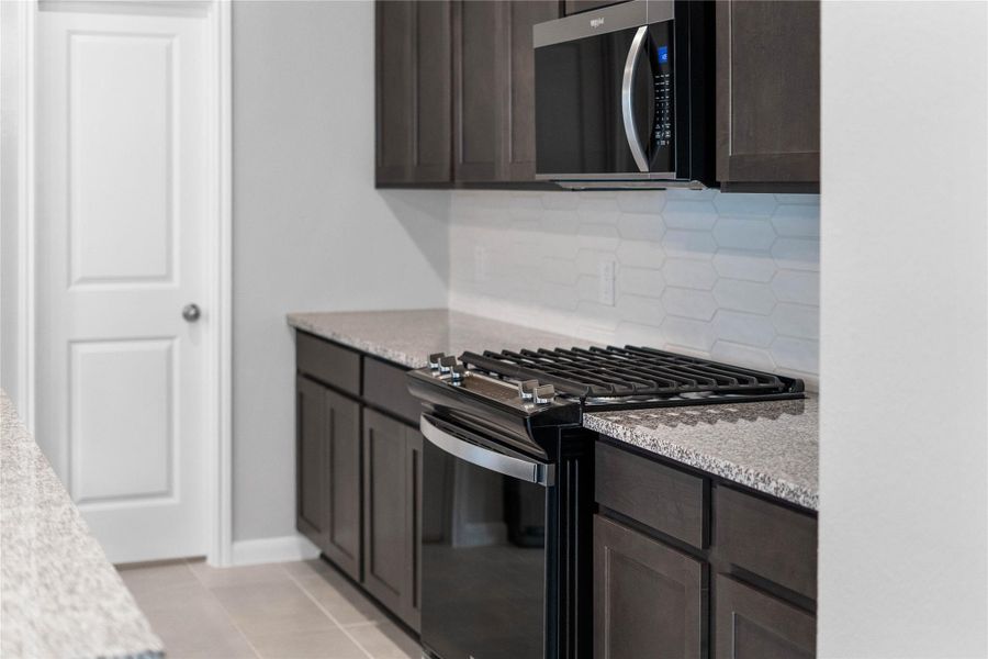 Showcased here is a Whirlpool Gas range, paired with a steam microwave equipped with sensor cooking—all framed by an elegant tile backsplash.