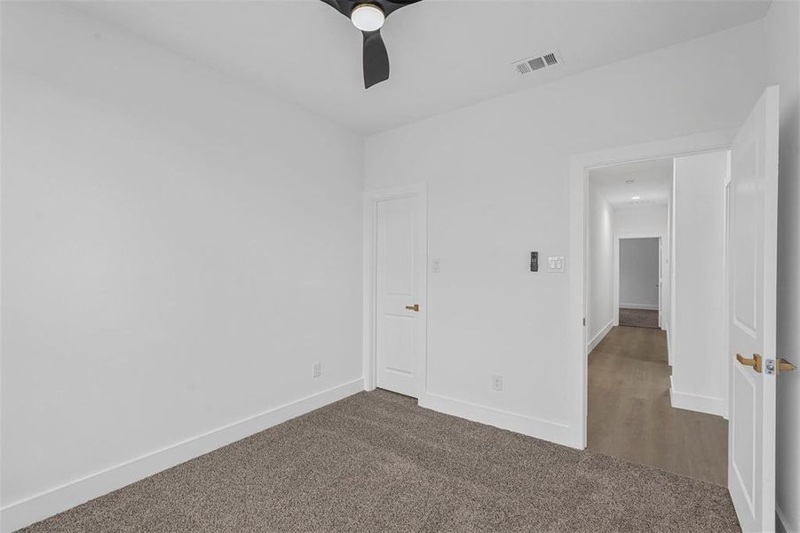 Unfurnished bedroom with dark carpet and a ceiling fan Unfurnished bedroom with dark carpet and a ceiling fan