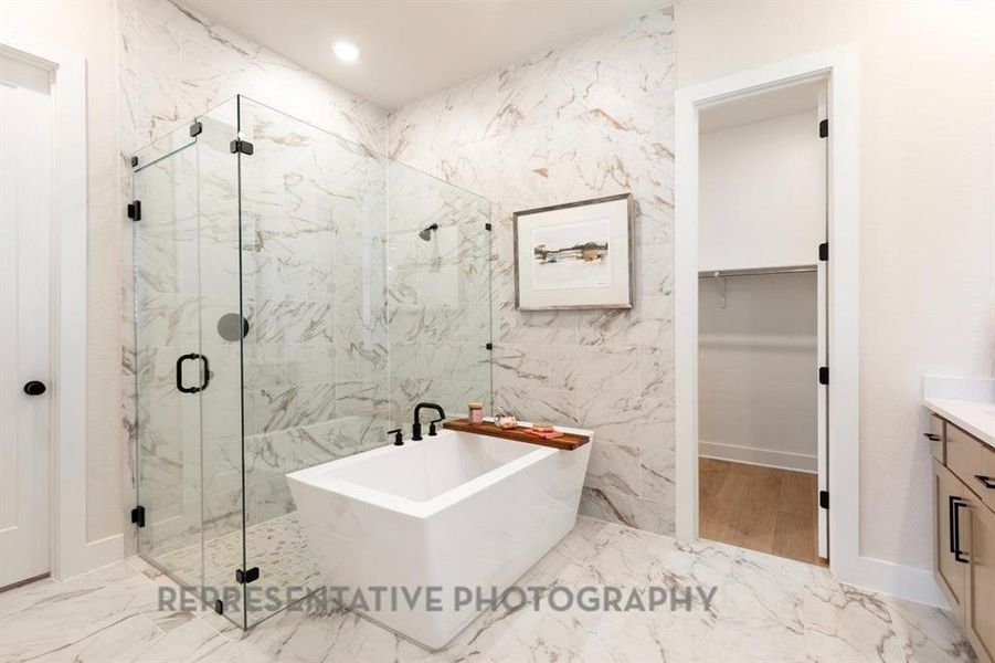 Full bathroom featuring vanity, a walk in closet, light marble finish flooring, a freestanding tub, and a marble finish shower Full bathroom featuring vanity, a walk in closet, light marble finish flooring, a freestanding tub, and a marble finish shower