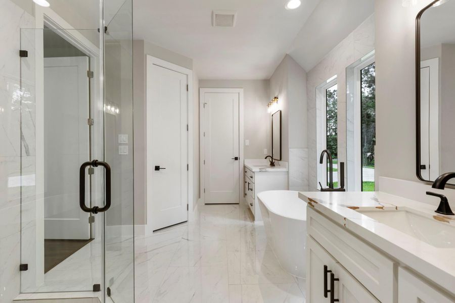 The modern freestanding tub with a sleek faucet with windows that offer a view of the wooded outdoors, creating a serene atmosphere and privacy.