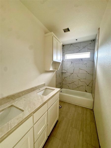 Dual vanities and a tiled bath create a pristine, functional bathing space.