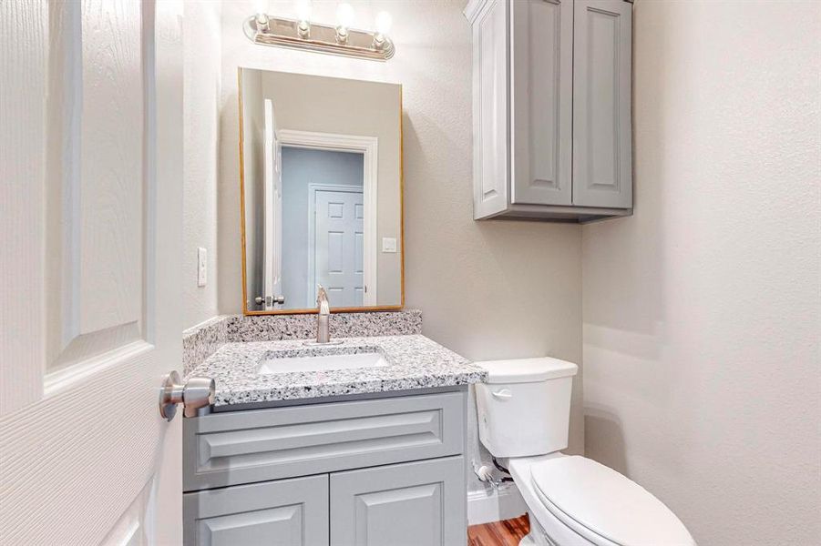 Bathroom with hardwood / wood-style floors, vanity, and toilet