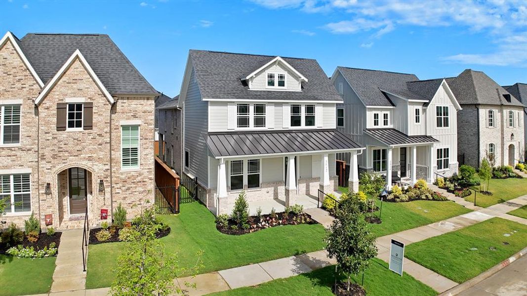 View of front of house with a standing seam roof, a metal roof, covered porch, brick siding, and a front lawn