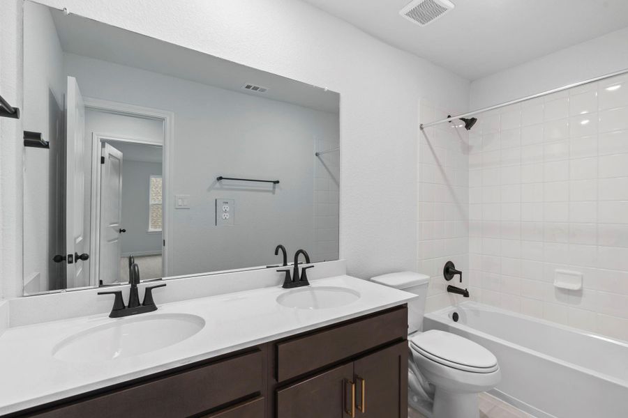The secondary bath features tile flooring, white cabinetry and light countertops and a shower/tub combo. Perfect for accommodating any visiting family and friends.
