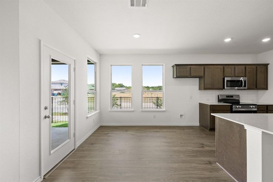 Kitchen with appliances with stainless steel finishes, dark brown cabinets, tasteful backsplash, and hardwood / wood-style flooring