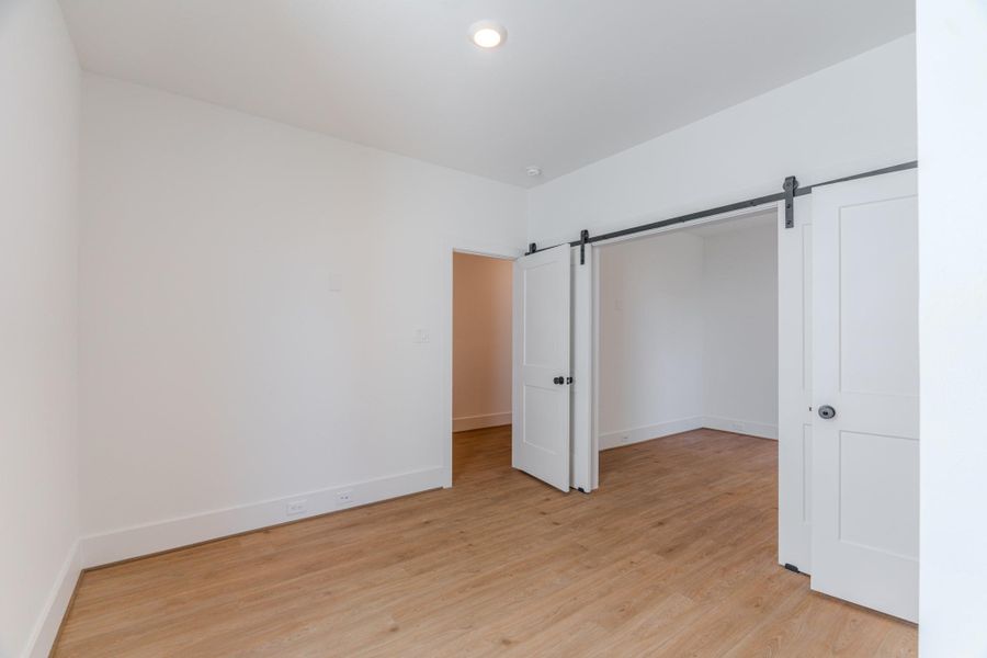 This room features clean white walls, hardwood floors, and ample natural light. It includes a stylish sliding barn door, adding a modern touch to the space.Photo Disclaimer: Photos are representative of the community and may depict a similar floor plan, model home, or previously completed residence. This room features clean white walls, hardwood floors, and ample natural light. It includes a stylish sliding barn door, adding a modern touch to the space.Photo Disclaimer: Photos are representative of the community and may depict a similar floor plan, model home, or previously completed residence.