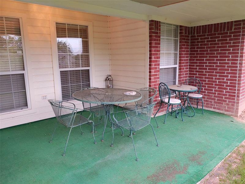 Covered patio featuring a red brick accent wall and light-colored siding