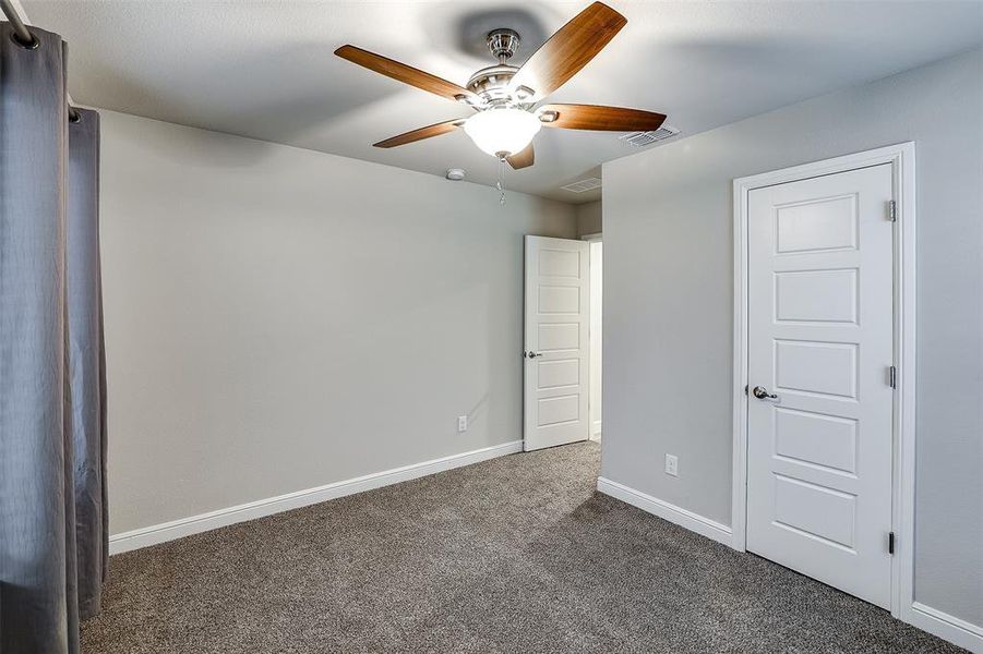 Unfurnished bedroom featuring dark colored carpet and ceiling fan Unfurnished bedroom featuring dark colored carpet and ceiling fan