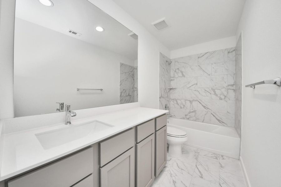 Secondary bath features tile flooring, bath/shower combo with tile surround, light stained wood cabinets, beautiful light countertop. Sample photo of completed home with similar floor plan. Actual colors and selections may vary. Secondary bath features tile flooring, bath/shower combo with tile surround, light stained wood cabinets, beautiful light countertop. Sample photo of completed home with similar floor plan. Actual colors and selections may vary.