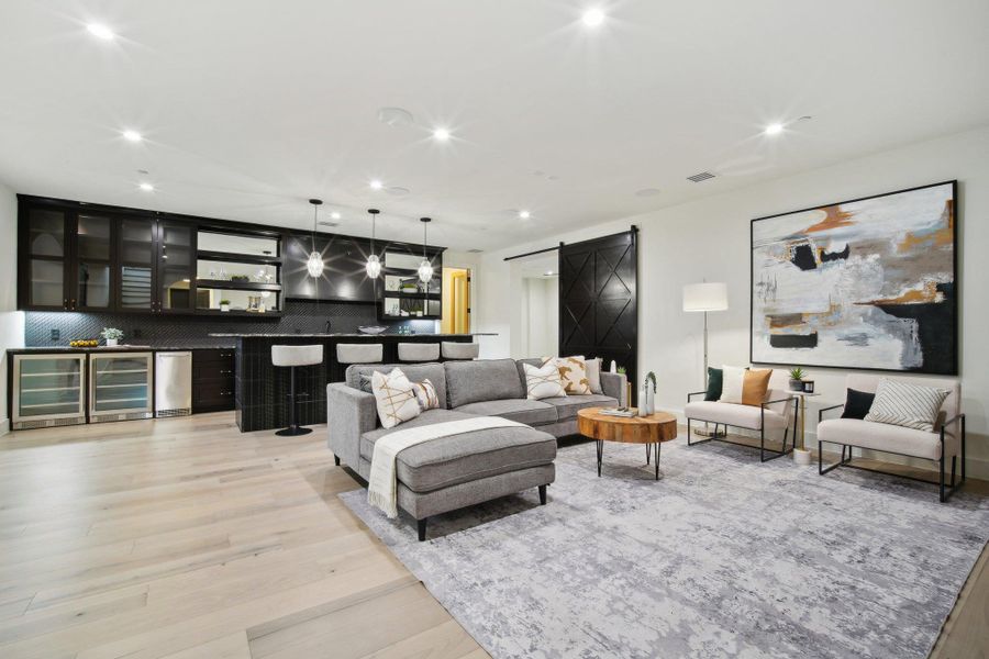 Living area with a barn door, wine cooler, and light wood finished floors