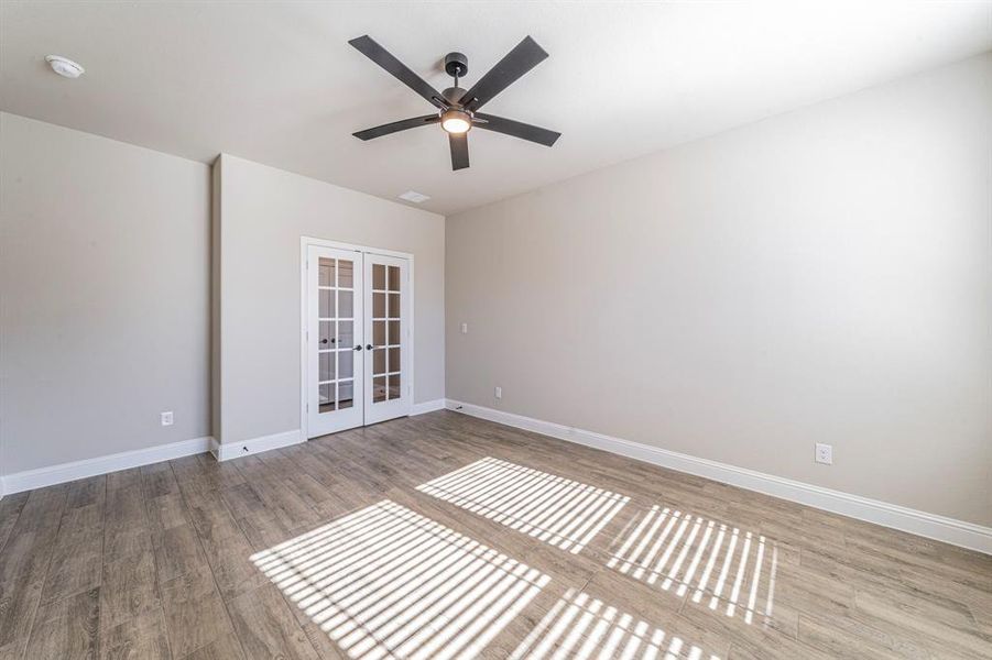 Spacious room featuring wood-finish flooring, light neutral wall paint, and white baseboards