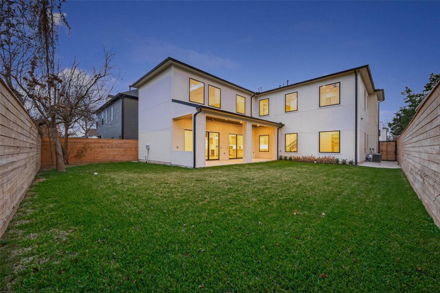 Expansive backyard with covered patio and large windows overlooking the lawn.