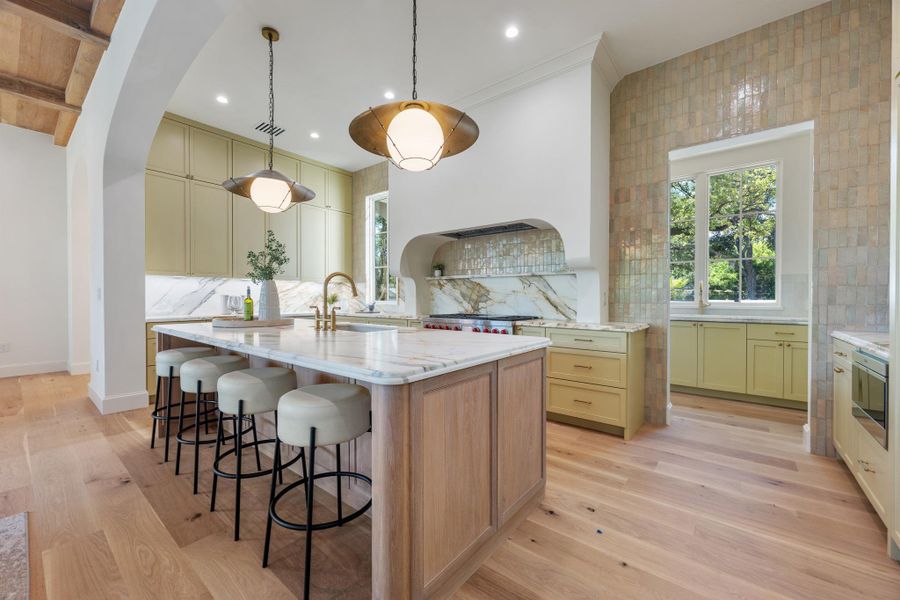 Rich wood floors and elegant stone countertops anchor this beautifully designed chef's kitchen.