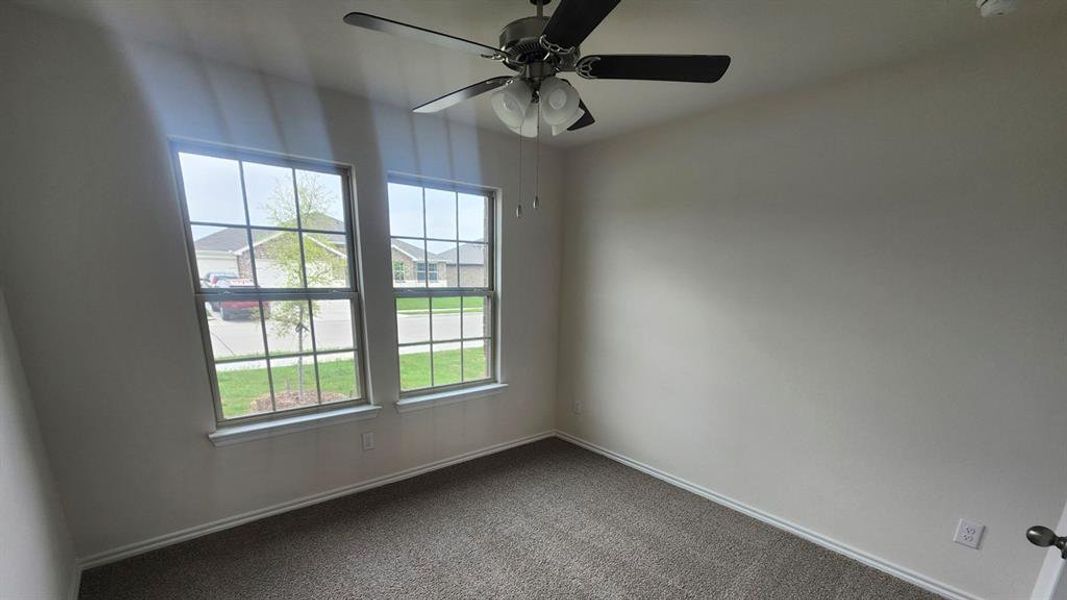 Room featuring two large windows, neutral-toned walls, gray carpet flooring, and a ceiling fan with integrated lighting