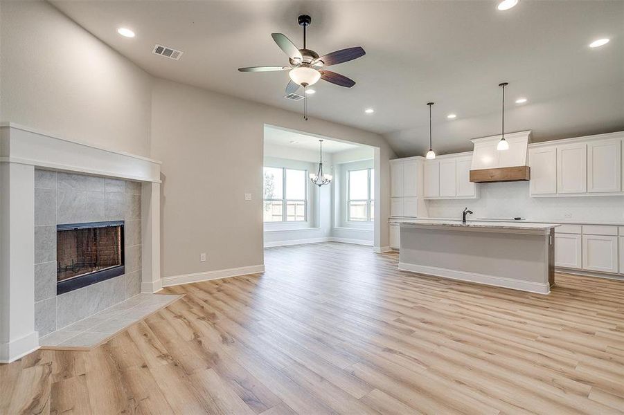 Kitchen with a fireplace, white cabinetry, light hardwood / wood-style flooring, and an island with sink