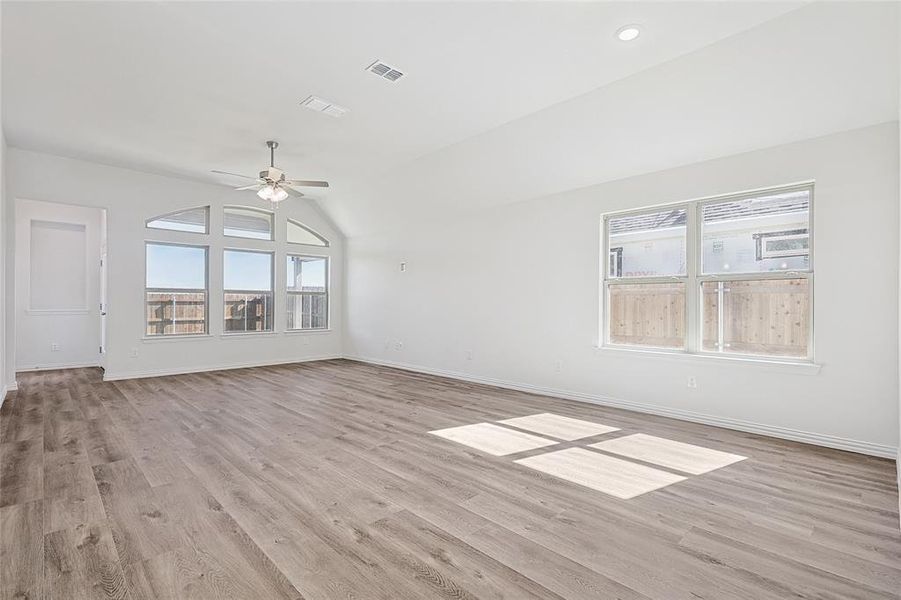 Unfurnished living room featuring light wood-type flooring, vaulted ceiling, and ceiling fan