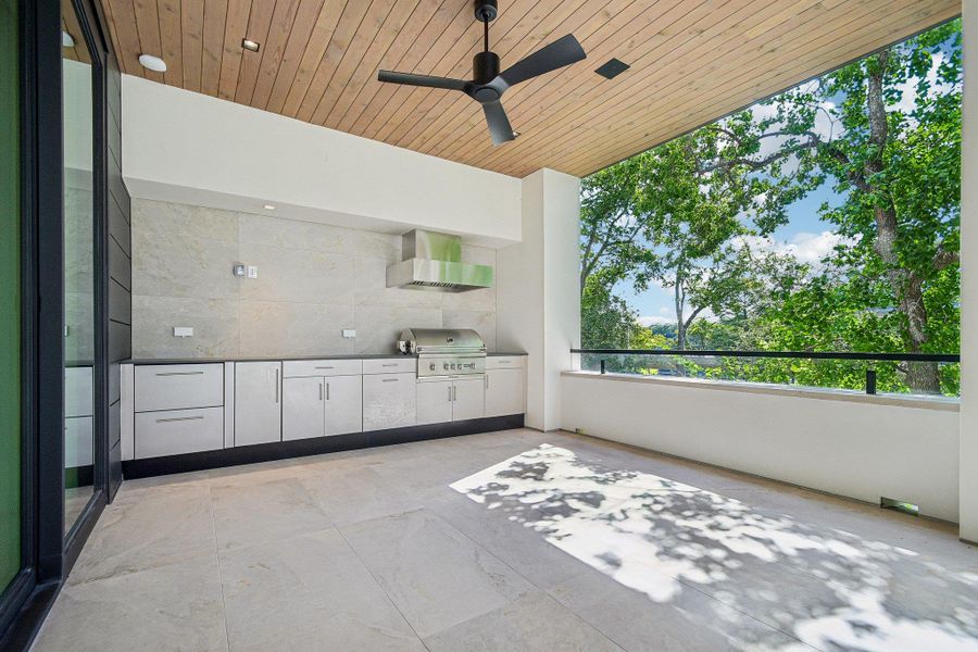 An covered terrace features tiled flooring, wood ceilings, and a modern outdoor kitchen. An covered terrace features tiled flooring, wood ceilings, and a modern outdoor kitchen.