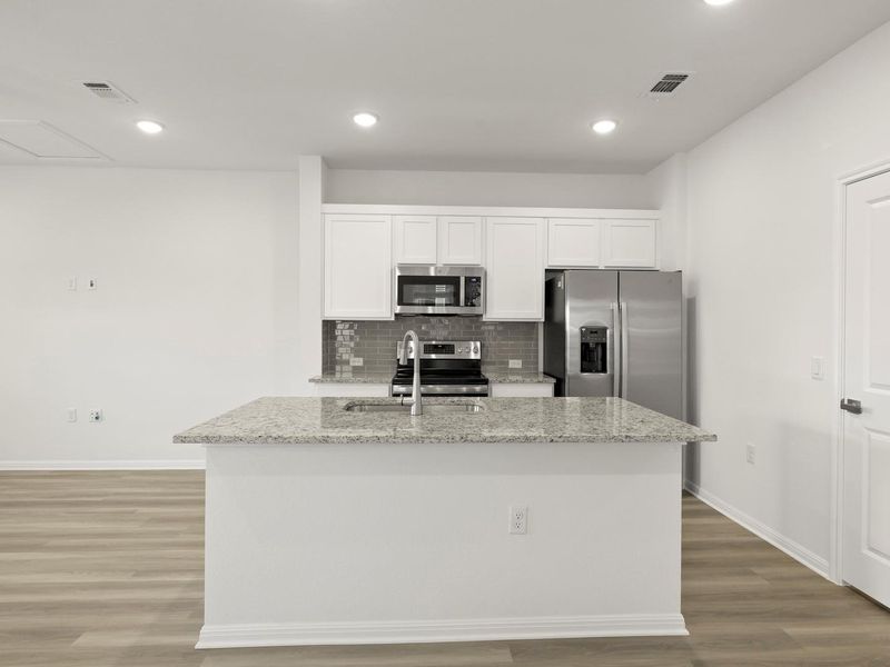 A well-appointed kitchen features a large island and contemporary stainless steel appliances.